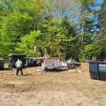 Multiple dumpsters on a lot where a camper is being destroyed