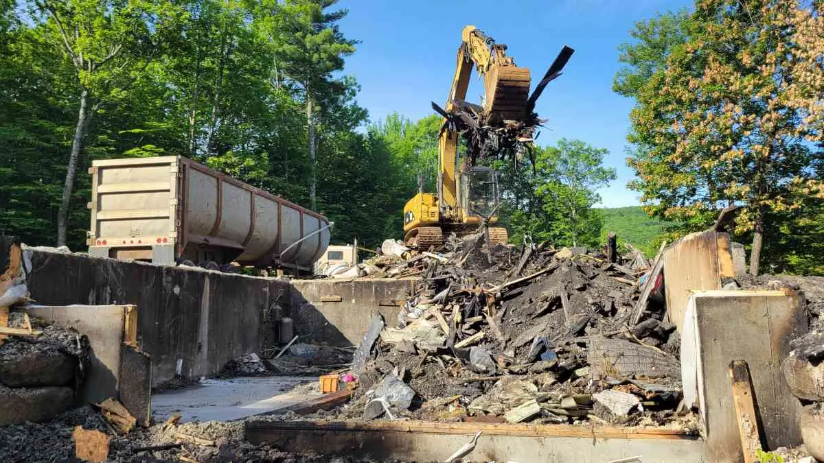 Reeds Dumpsters and Demolition LLC dump trailer being filled by excavator