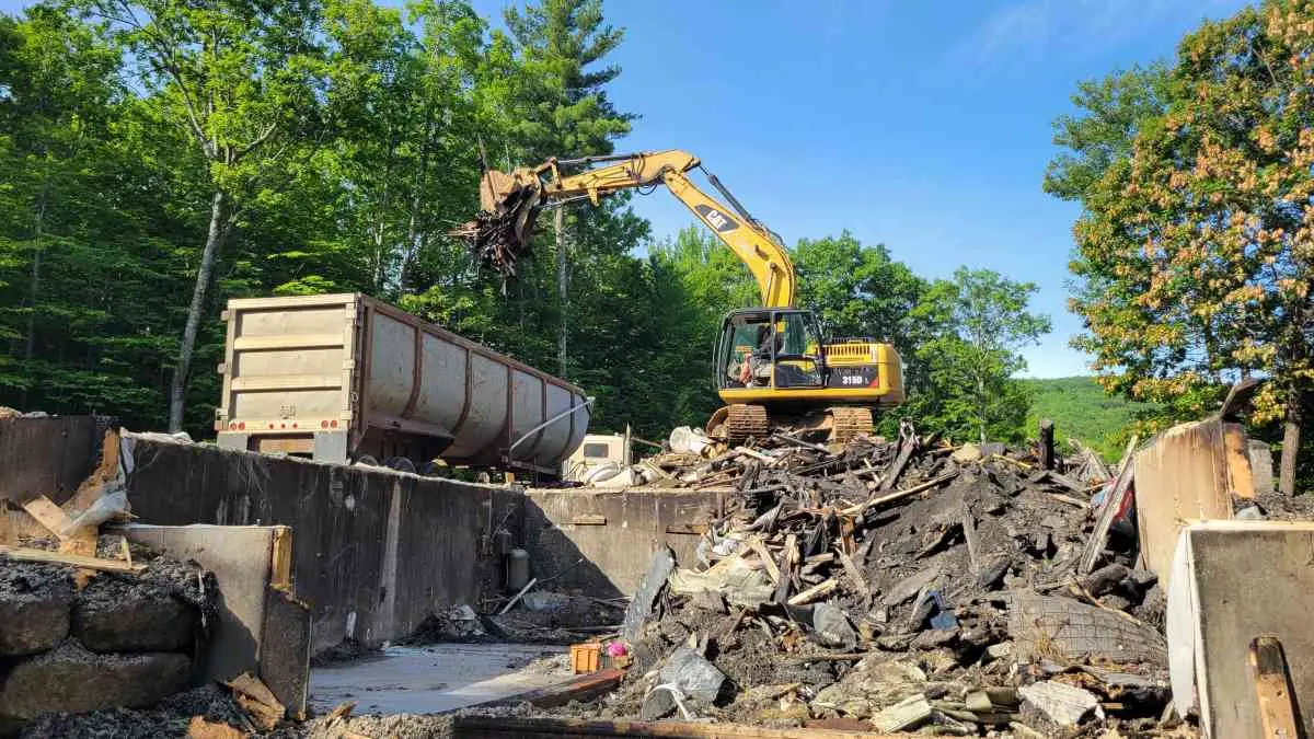 Reeds Dumpsters and Demolition LLC rental dumpster being loaded by excavator